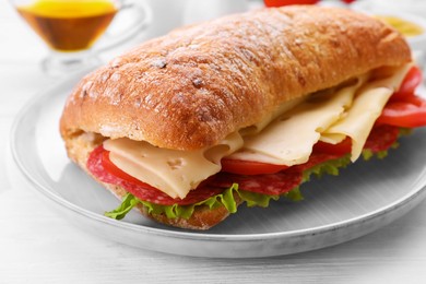 Delicious sandwich with cheese, salami, tomato on white wooden table, closeup