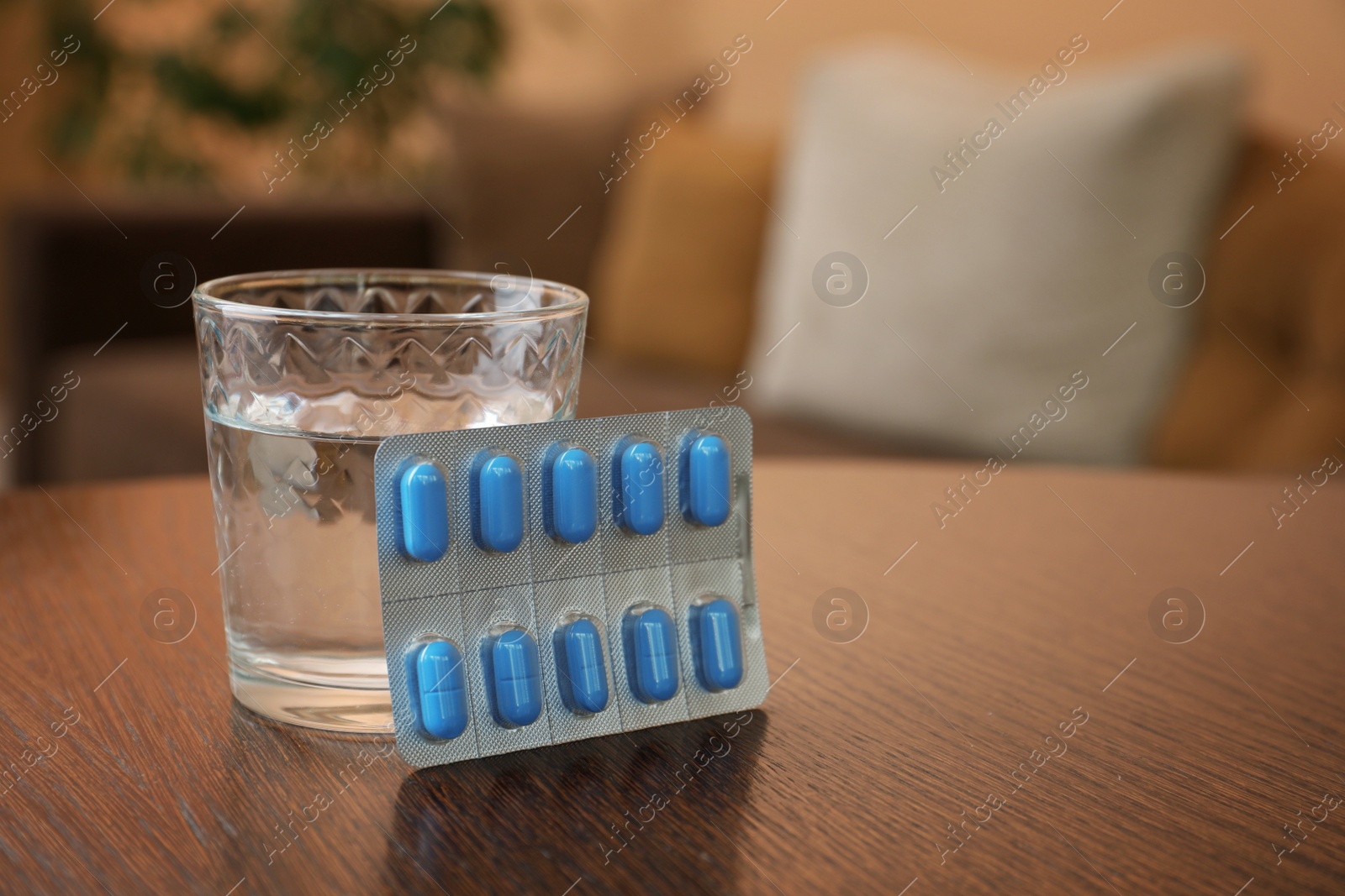 Photo of Glass of water and pills on wooden table indoors, space for text. Potency problem concept