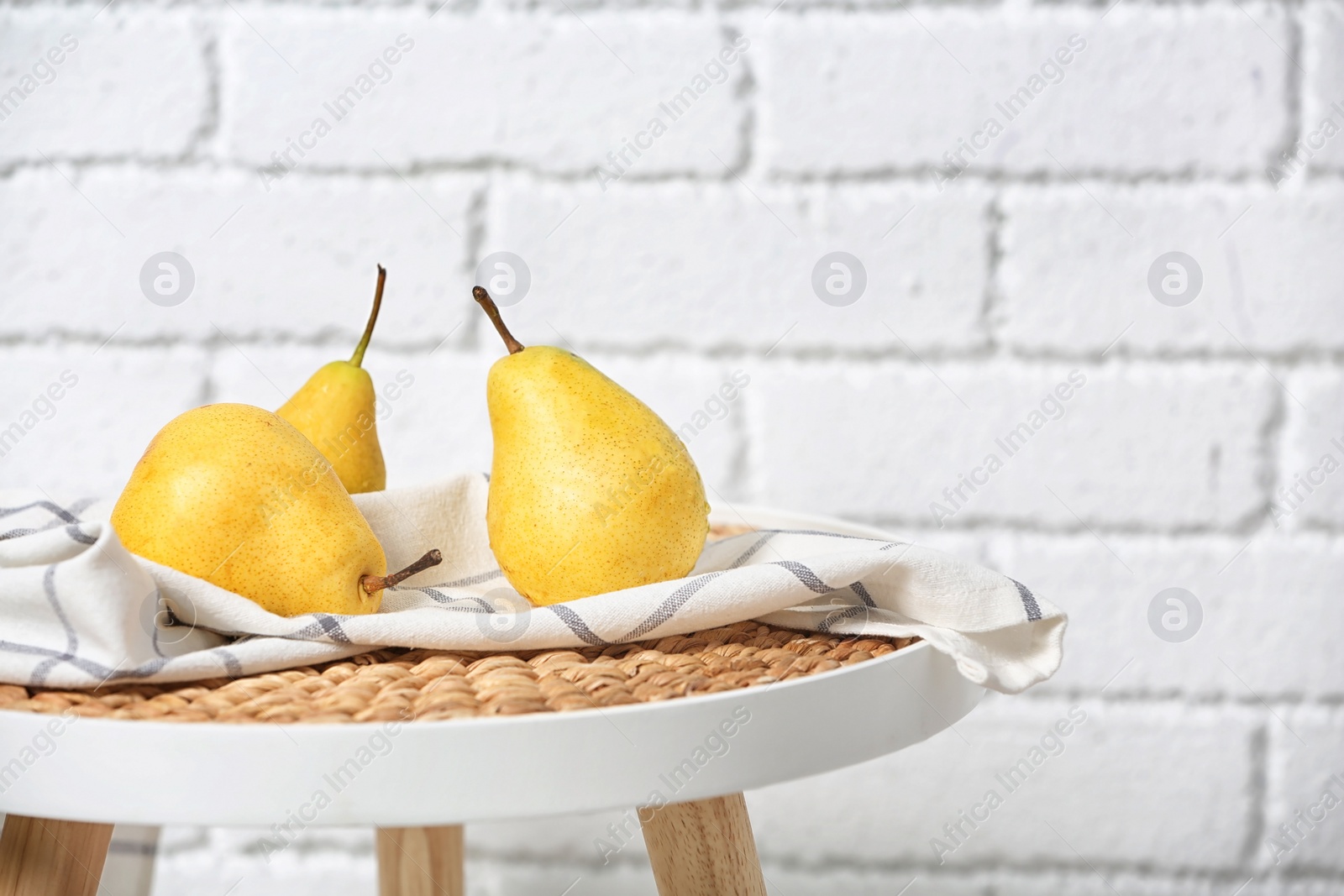 Photo of Ripe pears on table near brick wall. Space for text