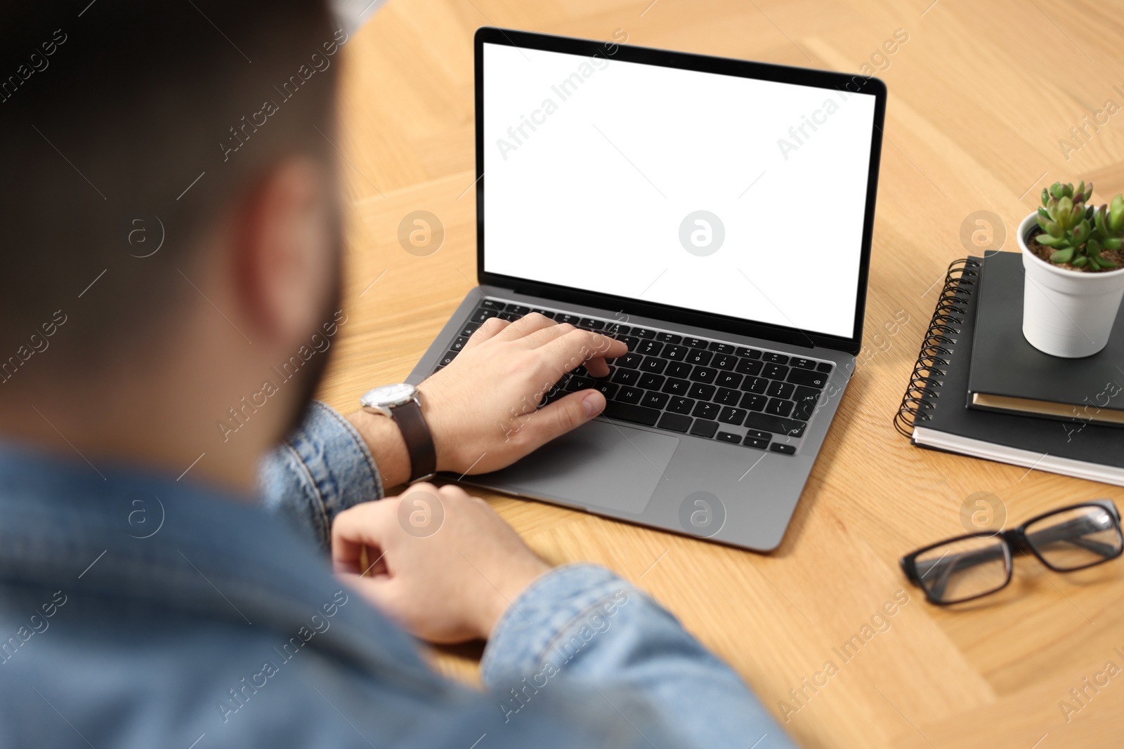 Photo of Young man watching webinar at table, closeup