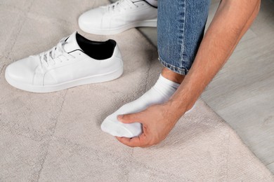 Man suffering from foot pain at home, closeup