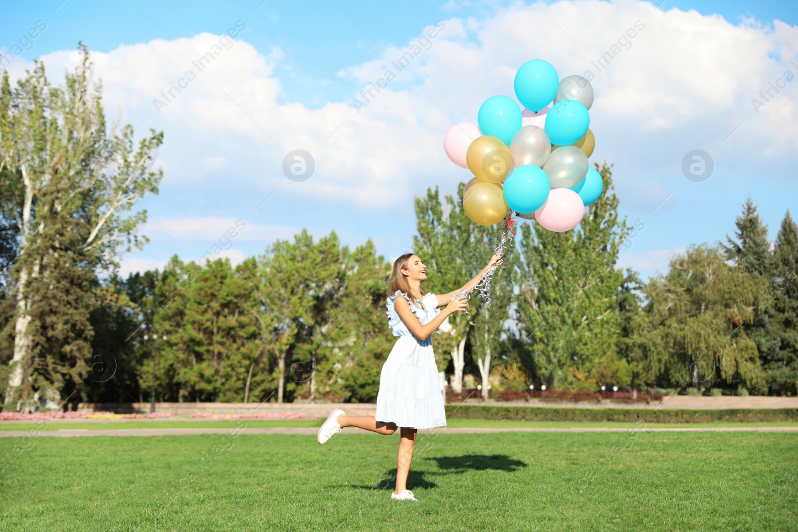 Photo of Beautiful teenage girl holding colorful balloons in park