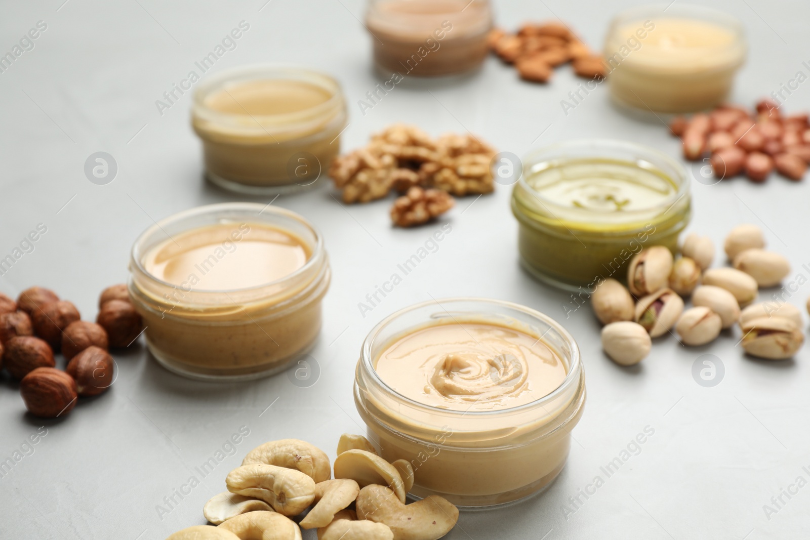 Photo of Different types of delicious nut butters and ingredients on light table