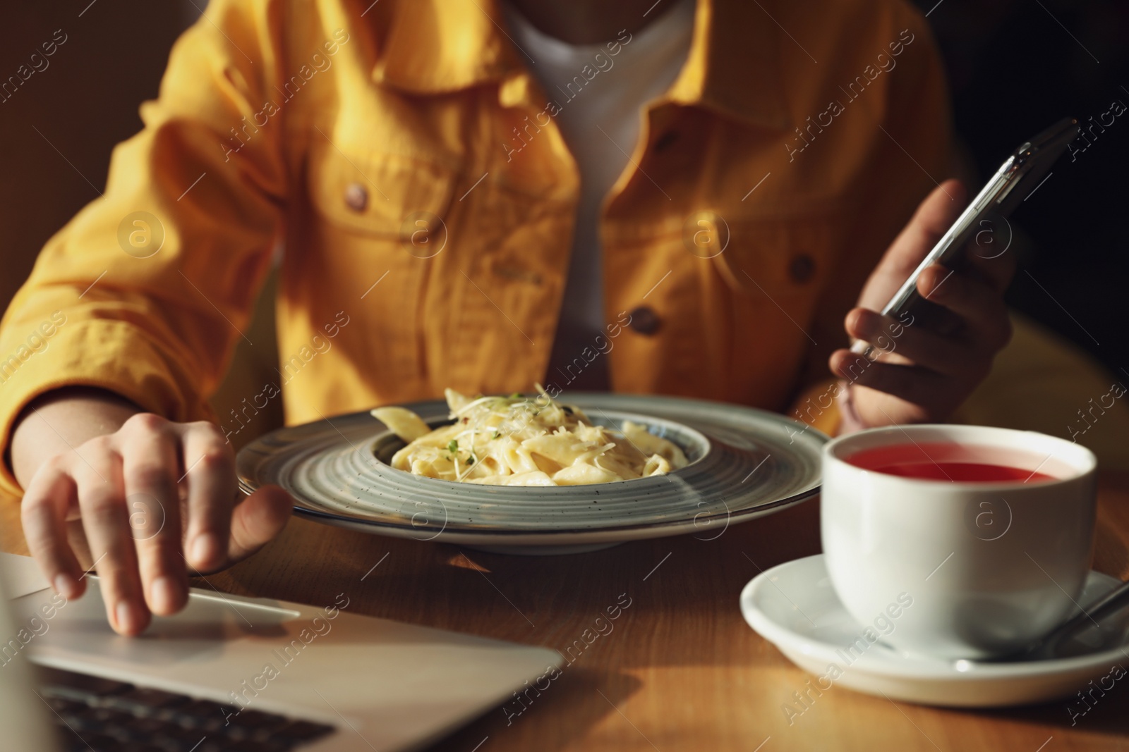 Photo of Young blogger working with laptop in cafe, closeup