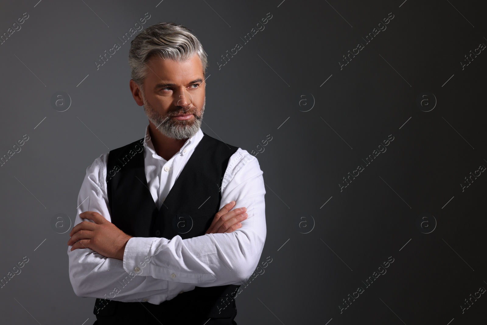 Photo of Portrait of confident man with beautiful hairstyle on dark background. Space for text