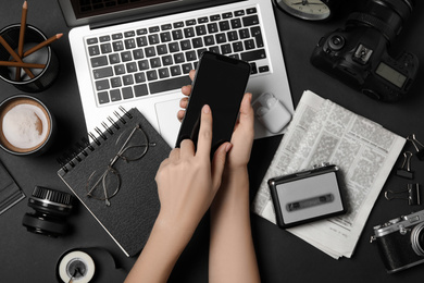 Photo of Journalist with smartphone working at black table, top view