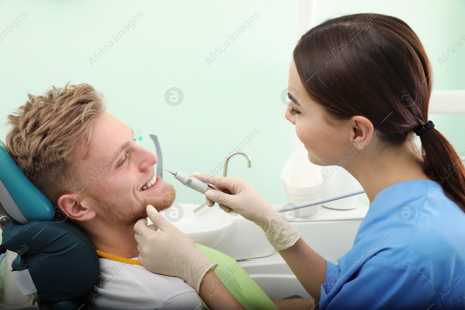 Photo of Professional dentist working with patient in modern clinic. Teeth whitening