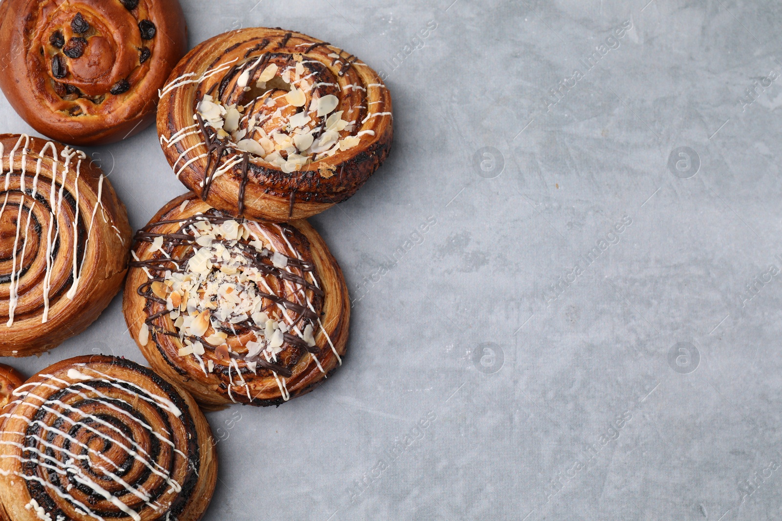 Photo of Different delicious rolls on light grey table, flat lay and space for text. Sweet buns