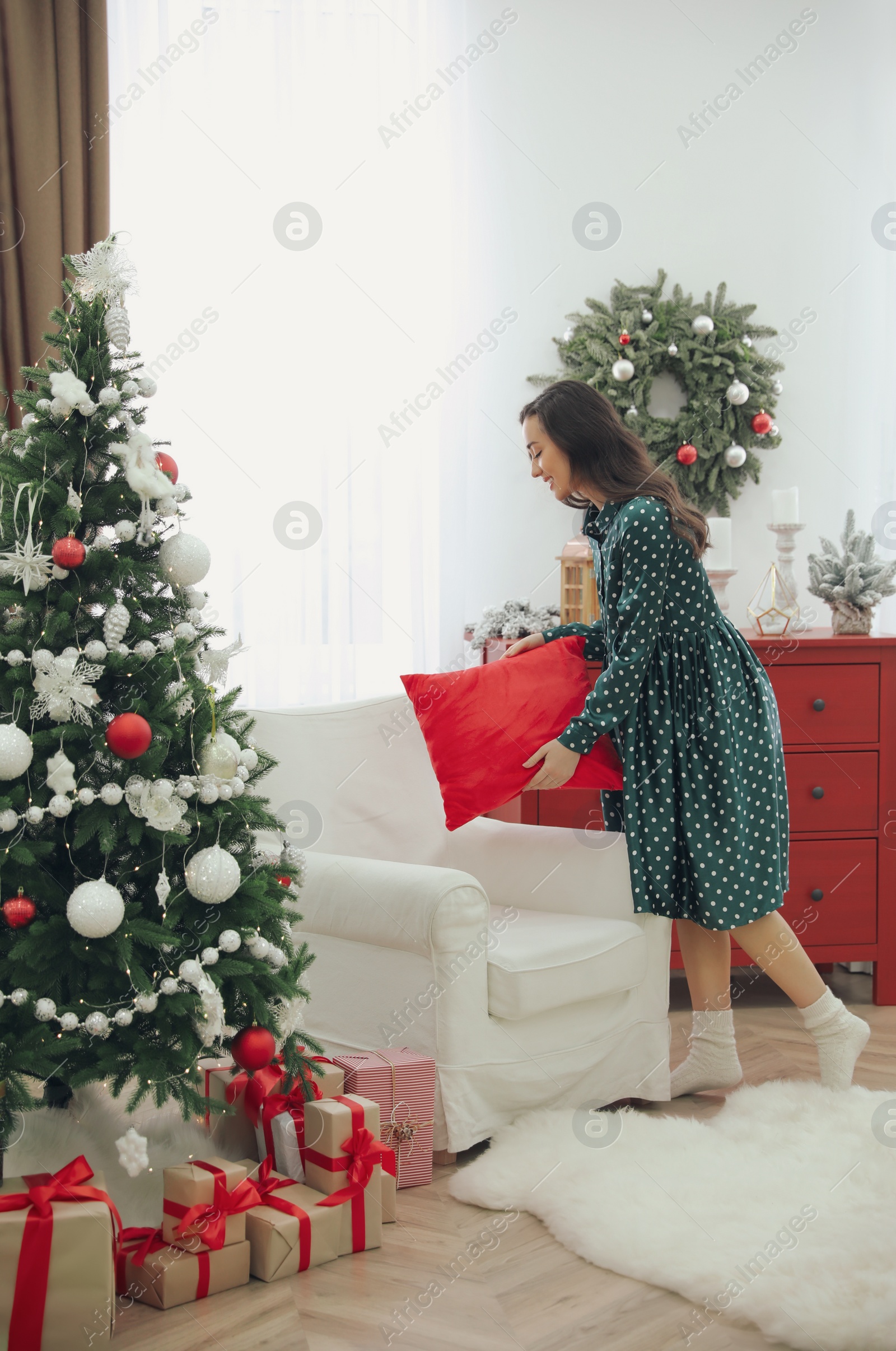 Photo of Woman putting decorative pillow on armchair at home