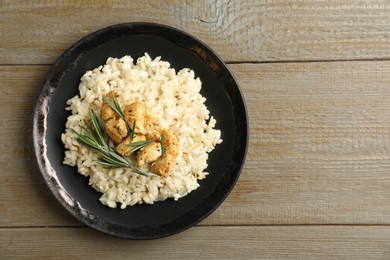 Delicious risotto with chicken on wooden table, top view