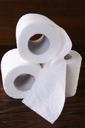 Photo of Many soft toilet paper rolls on wooden table, closeup