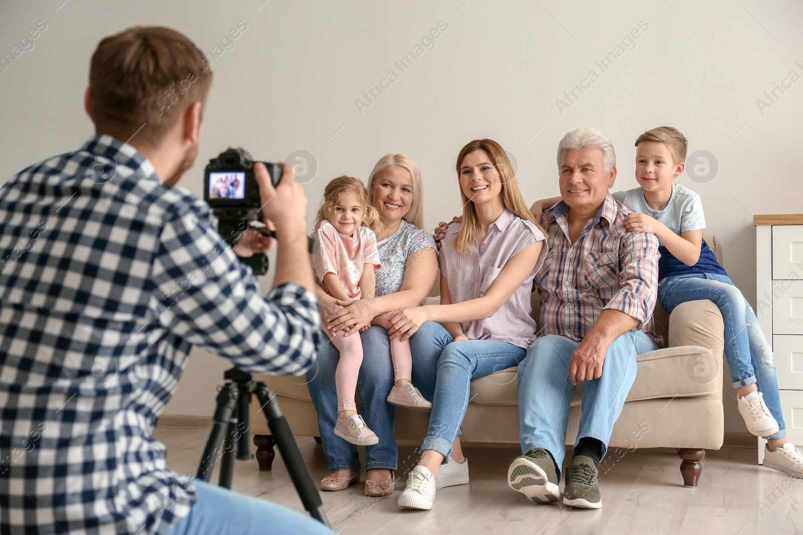 Photo of Professional photographer taking photo of family on sofa in studio