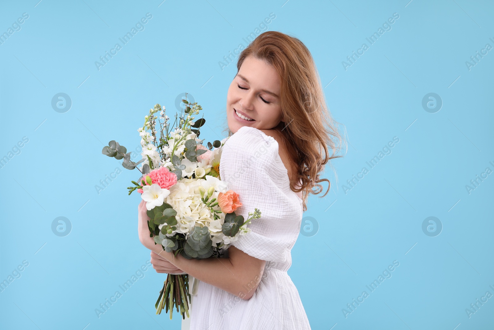 Photo of Beautiful woman with bouquet of flowers on light blue background