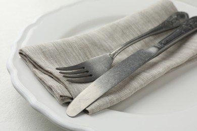 Stylish setting with cutlery, napkin and plate on white table, closeup