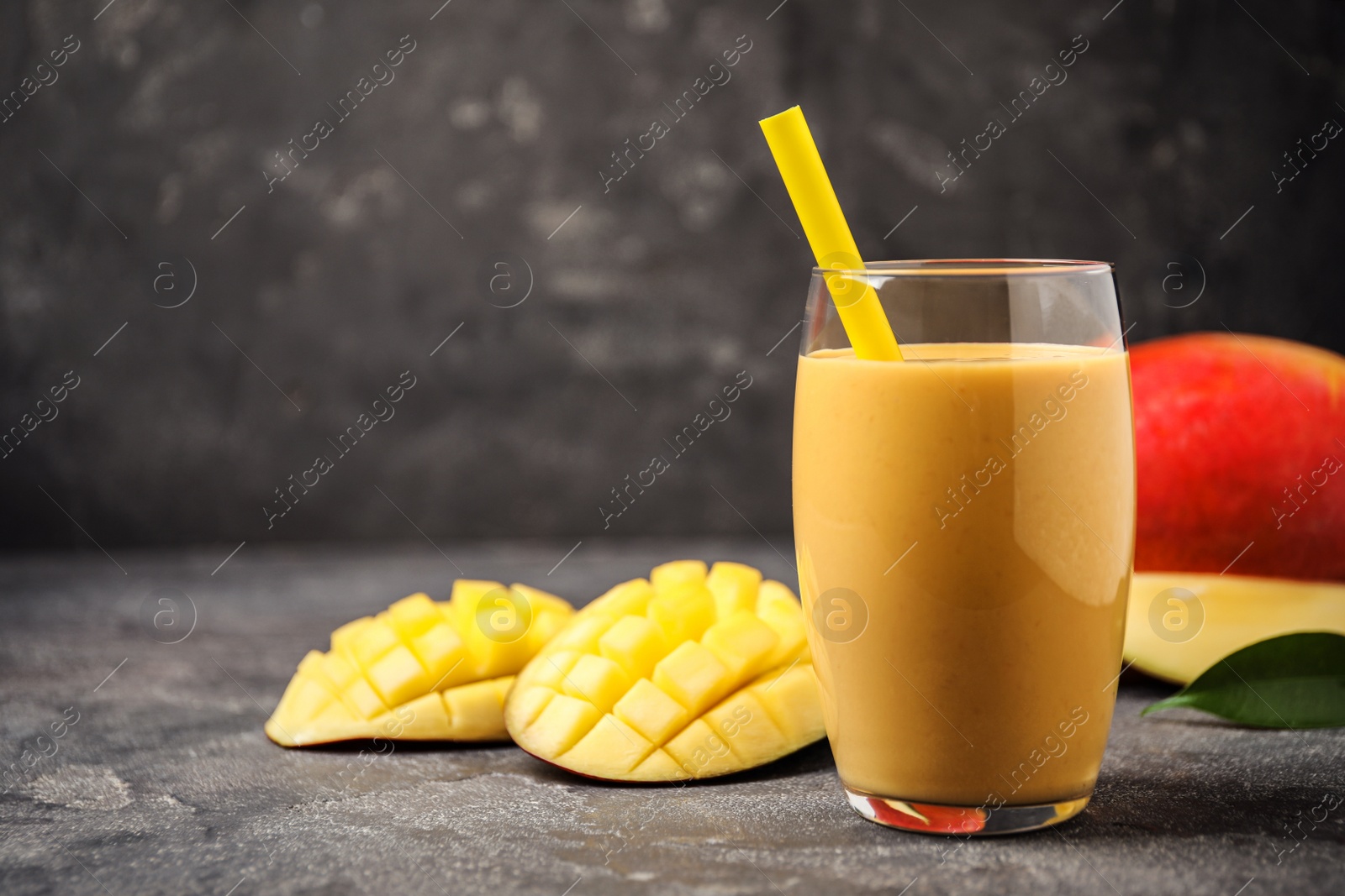 Photo of Fresh delicious mango drink on grey table. Space for text