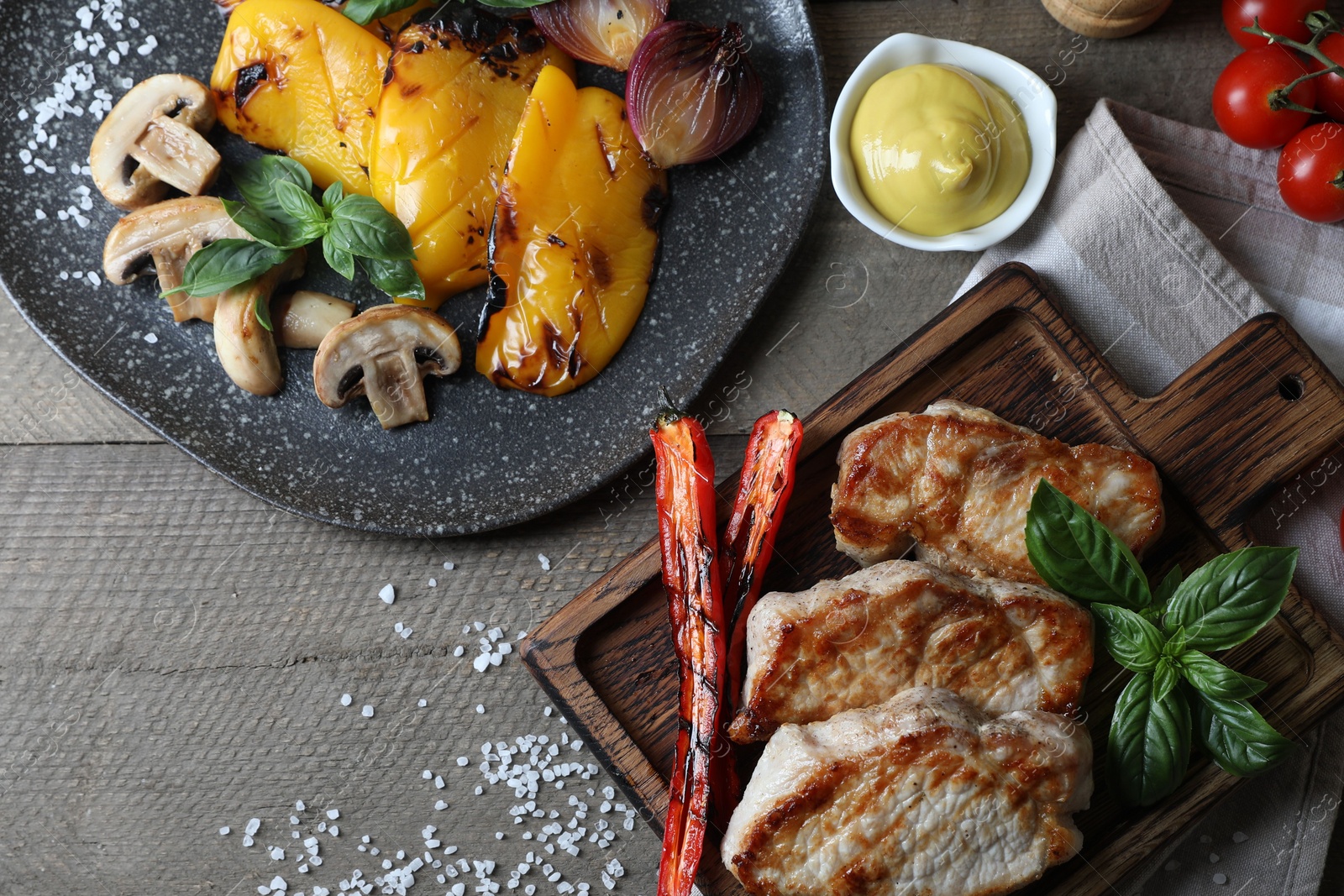 Photo of Delicious grilled meat and vegetables served on wooden table, flat lay