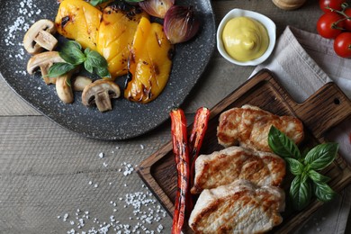 Delicious grilled meat and vegetables served on wooden table, flat lay