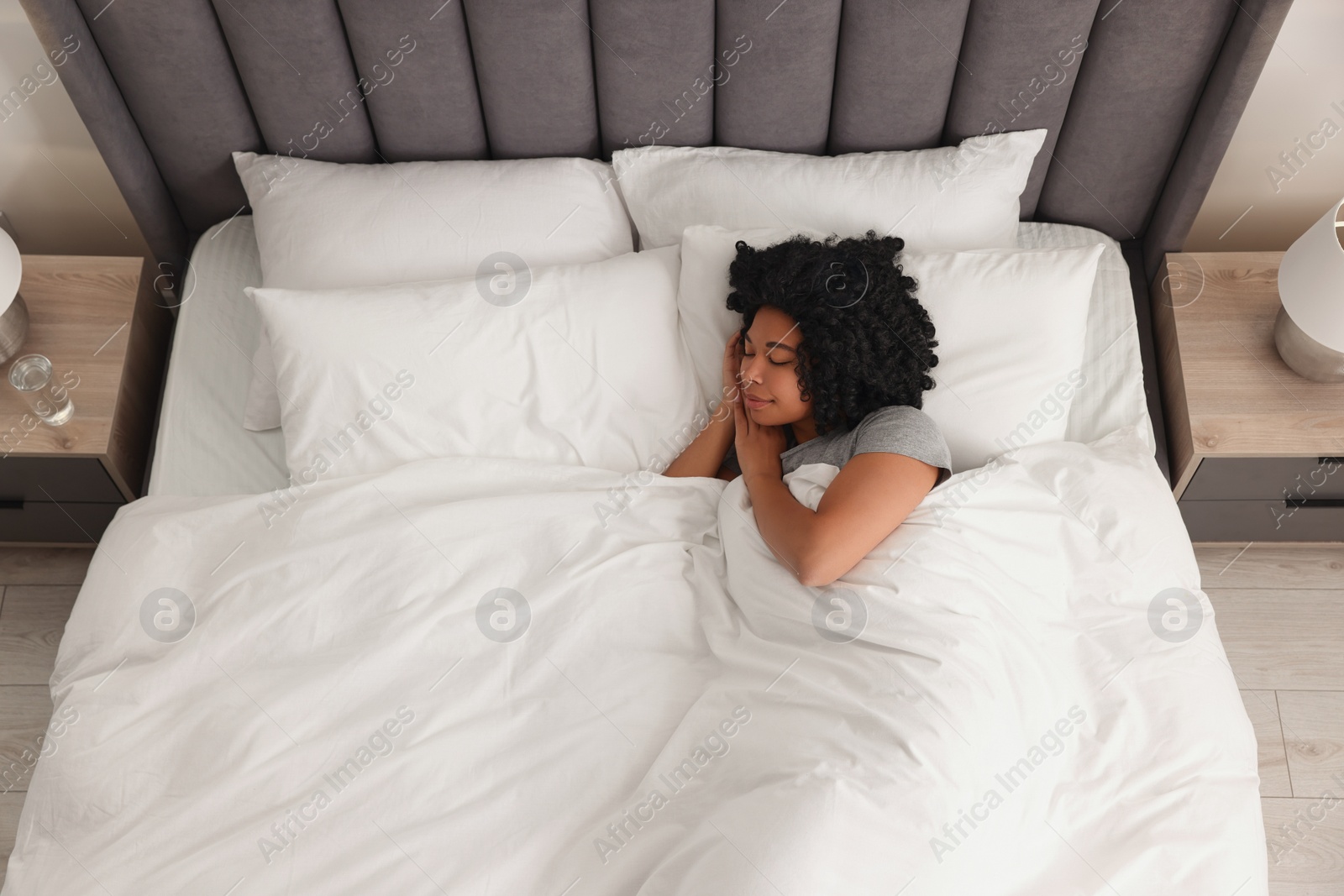 Photo of Beautiful young woman sleeping in soft bed at home, top view