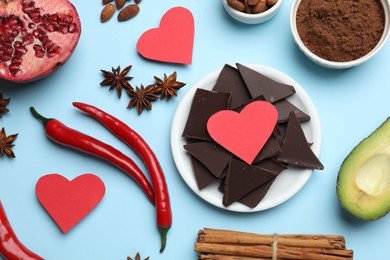 Photo of Natural aphrodisiac. Different products and paper hearts on light blue background, flat lay