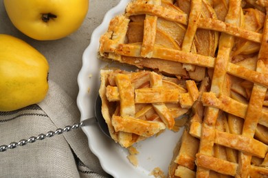 Photo of Tasty homemade quince pie with cake server and fresh fruits on light grey table, flat lay