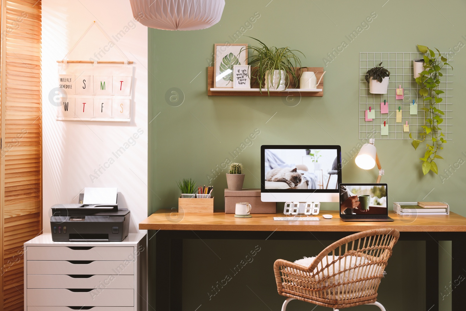 Photo of Stylish workplace with computer, laptop and lamp near olive wall at home