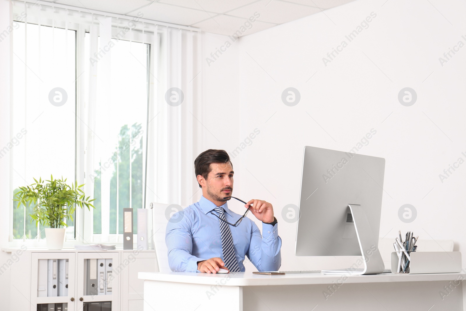 Photo of Handsome young man working with computer at table in office