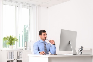 Handsome young man working with computer at table in office