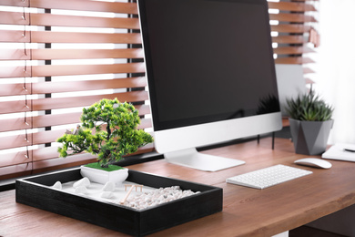 Photo of Modern workplace with beautiful miniature zen garden and computer in room