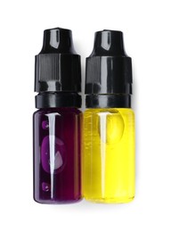 Bottles with yellow and purple food coloring on white background, top view