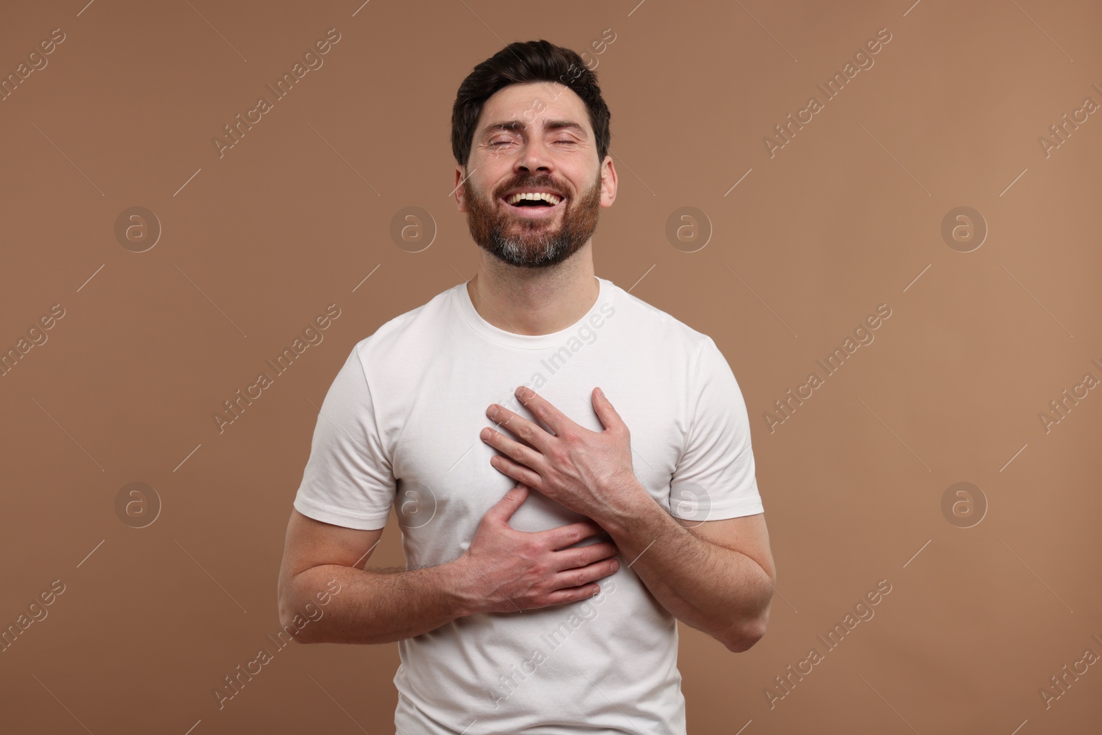 Photo of Handsome man laughing on light brown background