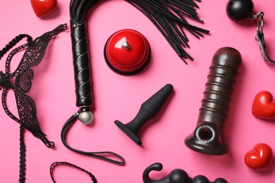 Photo of Set of different sex toys on pink background, flat lay