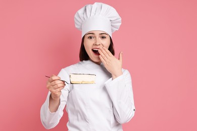 Happy confectioner with delicious cheesecake on pink background