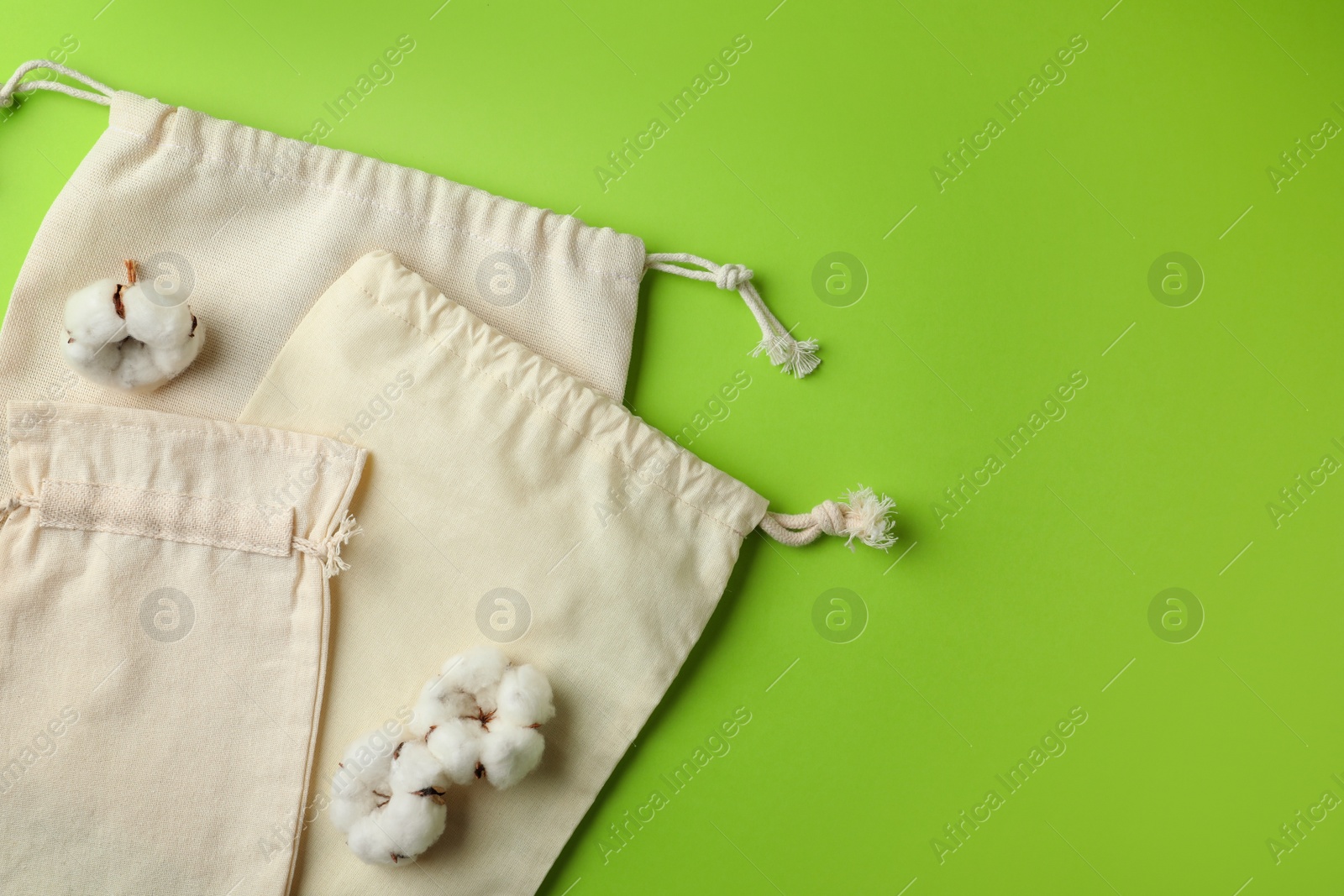 Photo of Cotton eco bags on light green background, flat lay