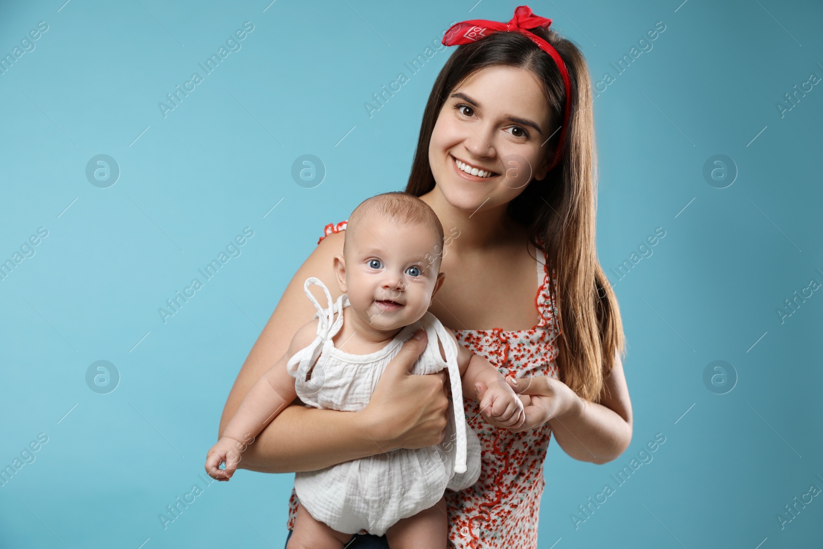 Photo of Beautiful mother with her cute baby on turquoise background