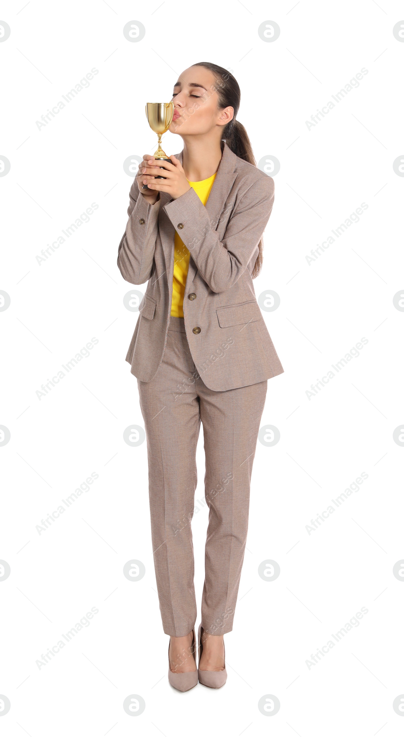 Photo of Full length portrait of young woman kissing gold trophy cup on white background