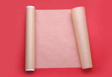 Roll of baking paper on red background, top view