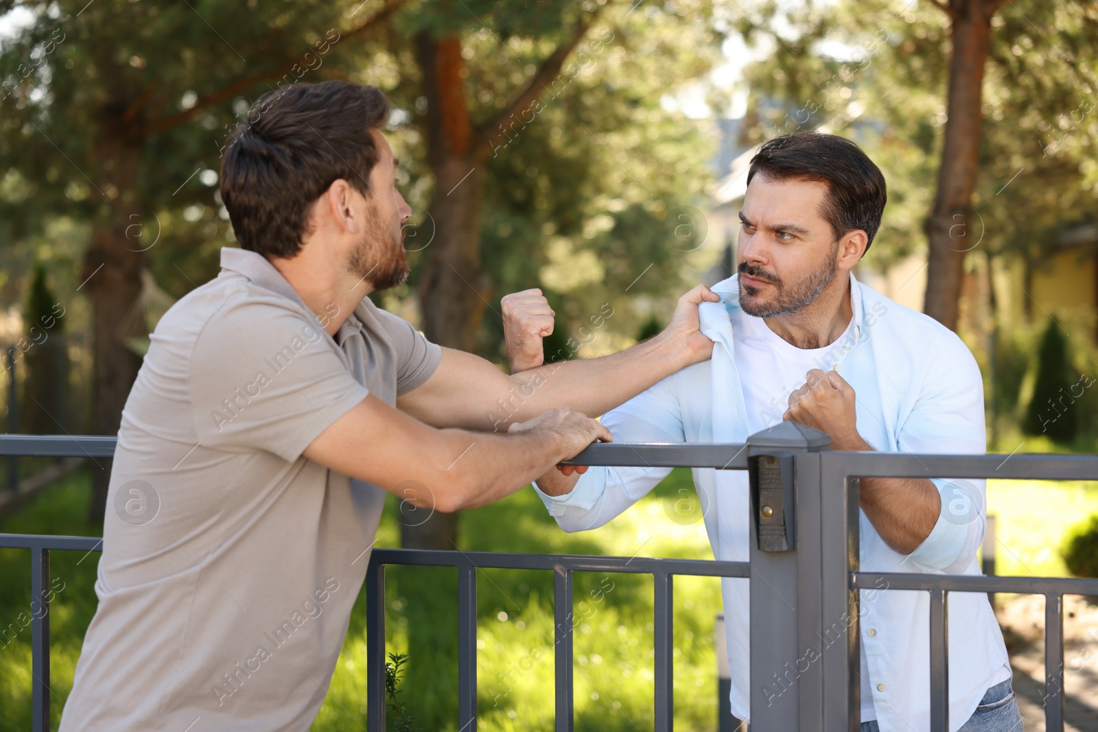 Photo of Angry neighbours having argument near fence outdoors