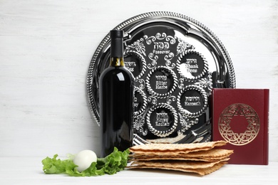 Photo of Symbolic Passover (Pesach) items on table against wooden background, space for text