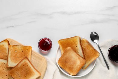 Photo of Slices of tasty toasted bread and jam on white marble table, flat lay. Space for text
