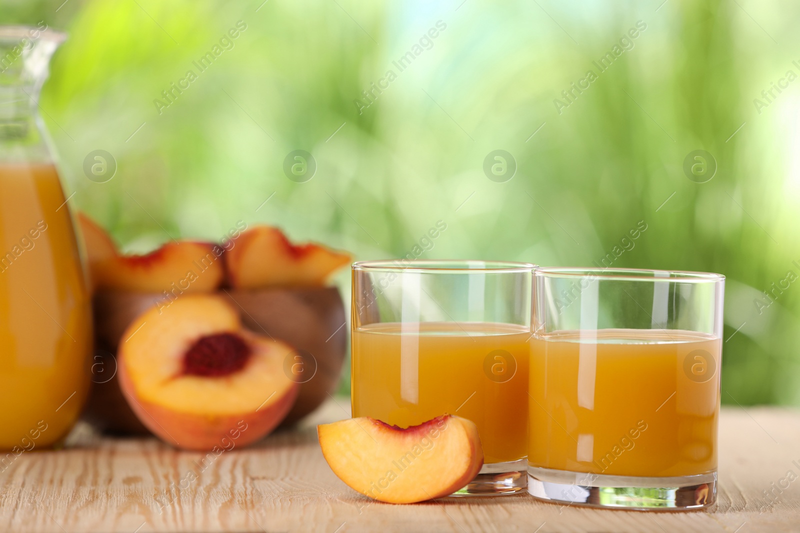 Photo of Tasty peach juice and fresh fruits on wooden table outdoors, space for text