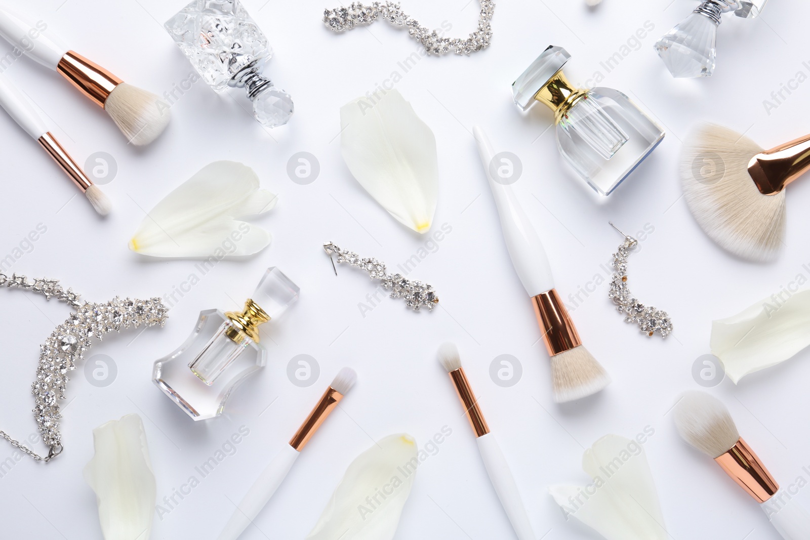 Photo of Bottles of perfume, makeup brushes and accessories on white background, flat lay