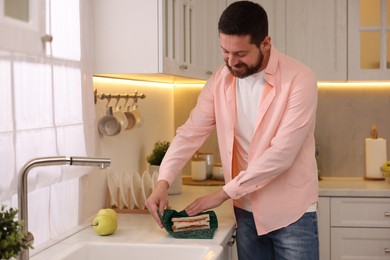 Man packing sandwich into beeswax food wrap at countertop in kitchen