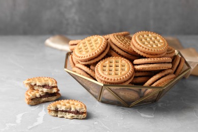 Photo of Tasty sandwich cookies with cream on grey table, closeup