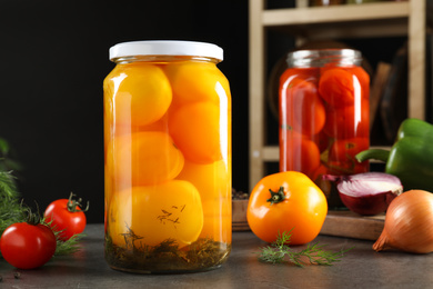 Glass jars of pickled tomatoes on grey table