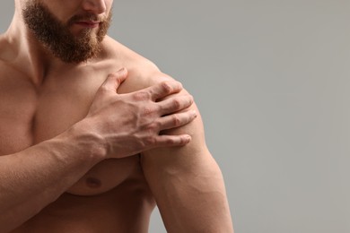 Man with muscular body on light grey background, closeup. Space for text