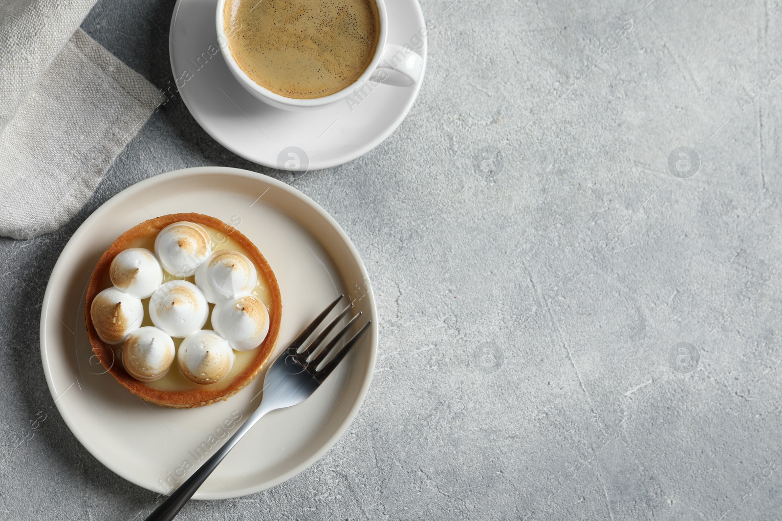 Photo of Tasty dessert. Tartlet with meringue and cup of coffee on light grey table, flat lay. Space for text