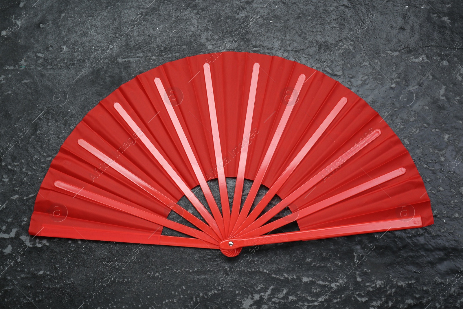 Photo of Bright red hand fan on grey textured background, top view
