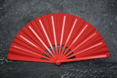 Bright red hand fan on grey textured background, top view