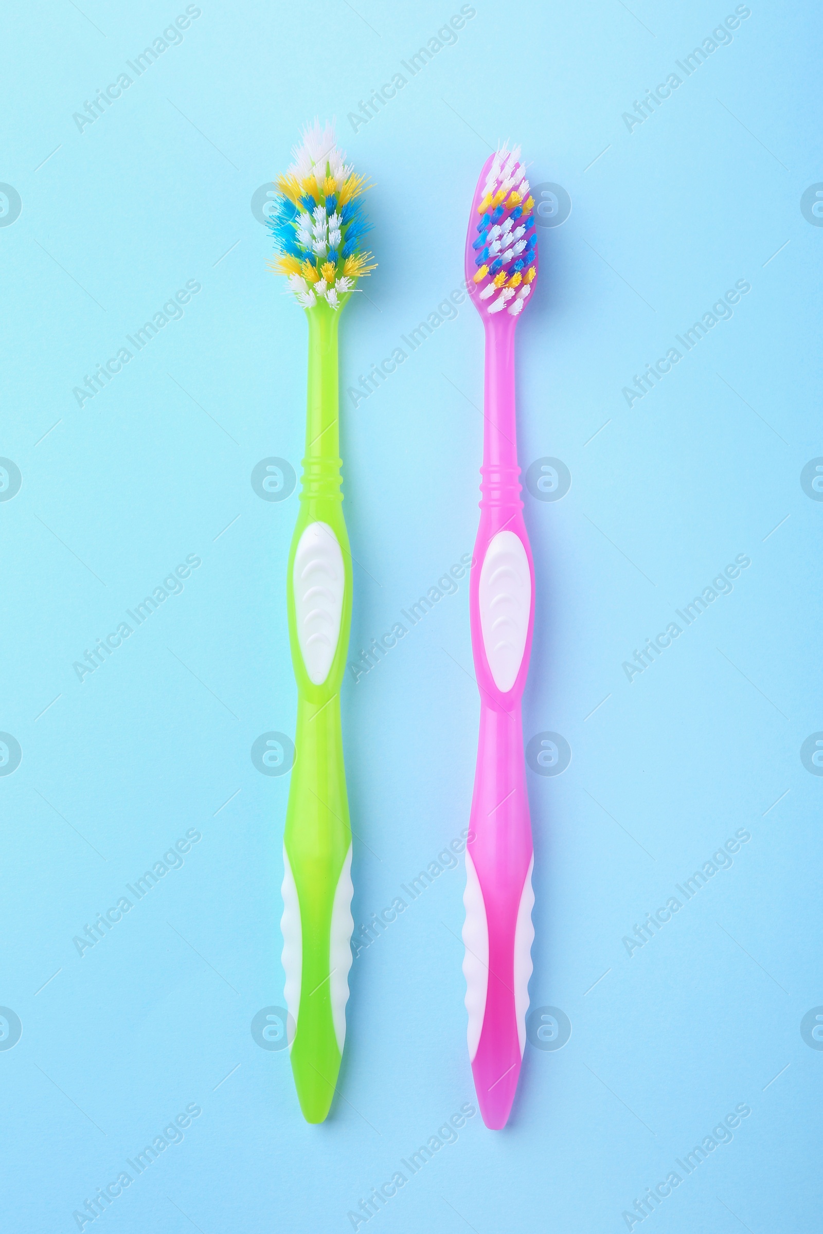 Photo of Colorful plastic toothbrushes on light blue background, flat lay