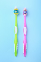 Photo of Colorful plastic toothbrushes on light blue background, flat lay